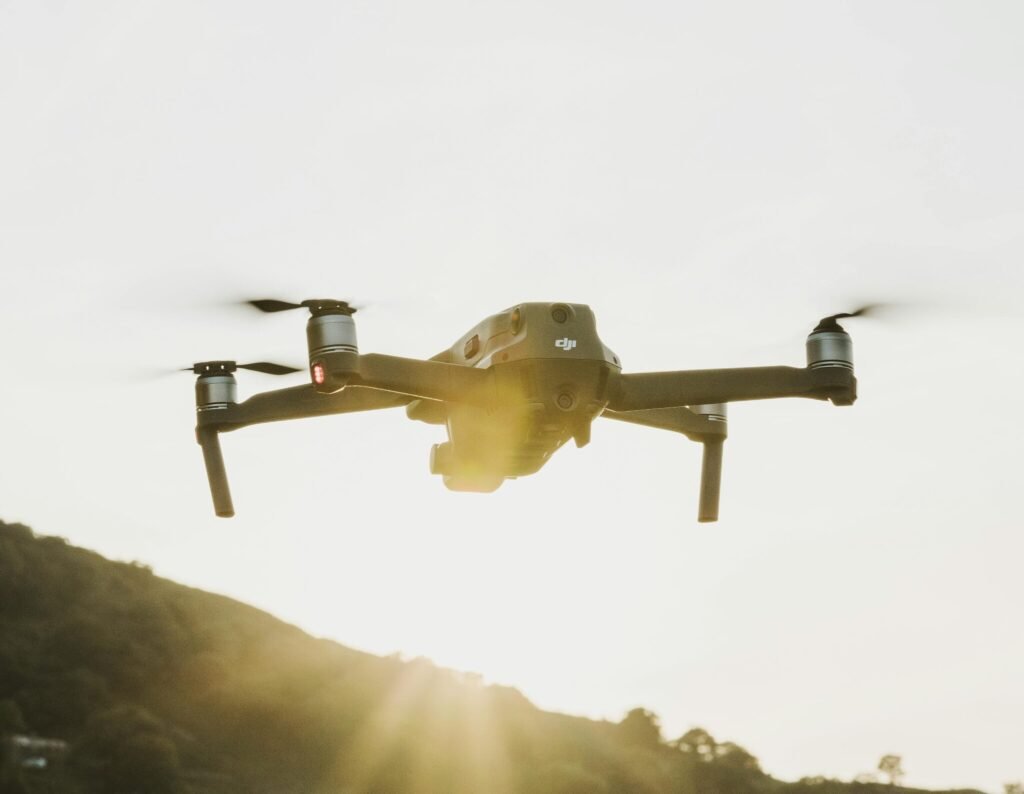 A drone flying over hilly terrain during sunrise, showcasing technology and aerial capability.